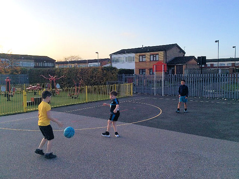 Children in the playground learning how to play basketball